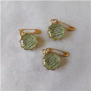 سنجاق سینه نوزادی شبتاب سبز رزینی مزین به وان یکاد و پشت قاب حرز صغیر امام جواد(ع) قاب برنج طلایی