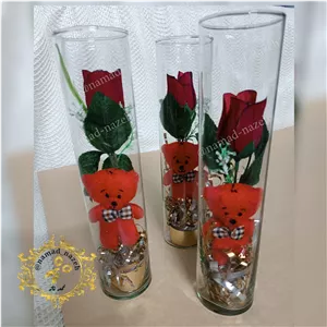 استوانه گل شاخه گل رز مصنوعی و خرس قرمز در استوانه شیشه ای مناسب هدیه به عزیزانتان